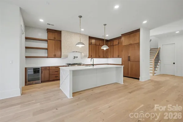 a large kitchen with a large counter top a sink stainless steel appliances and cabinets