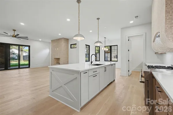 a large kitchen with stainless steel appliances kitchen island granite countertop a stove a sink a dining table and chairs with wooden floor