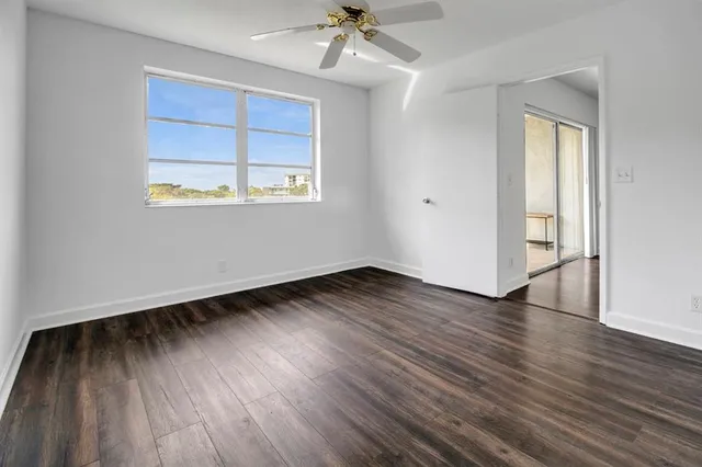 an empty room with wooden floor chandelier and windows