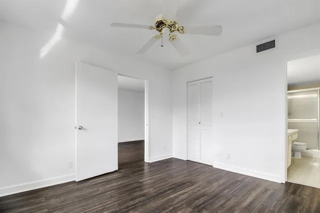 a view of an empty room with wooden floor and a ceiling fan