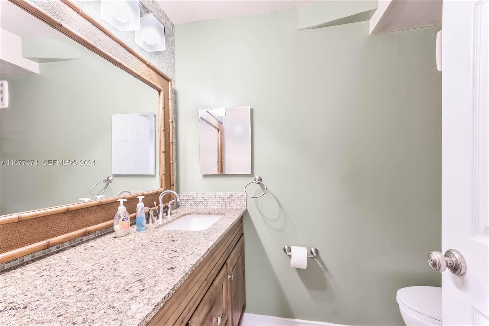 301 Racquet Club Road, Unit 108 Weston, FL 33326 - Photo 15 of 30 a bathroom with a granite countertop sink and a large mirror