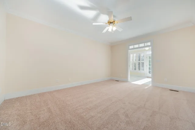 an empty room with windows and chandelier fan