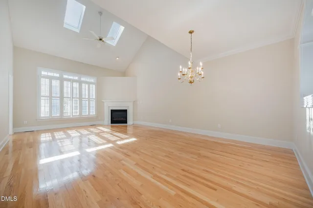 a view of an empty room with window and wooden floor