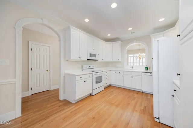 a kitchen with white cabinets and wooden floors