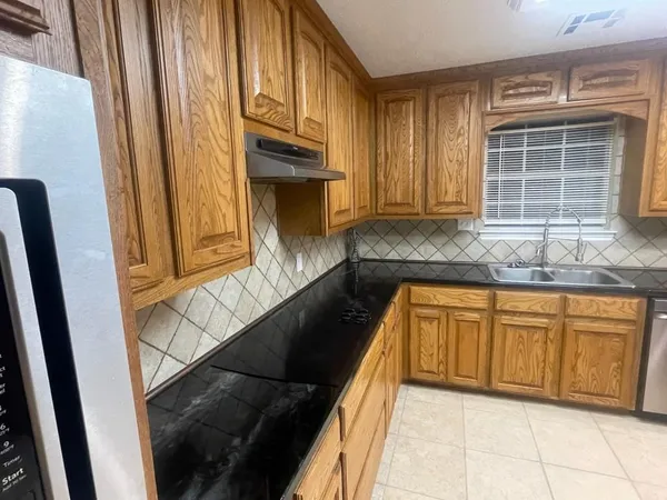 a kitchen with granite countertop white cabinets and stainless steel appliances