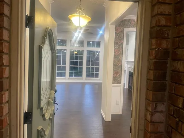 a view of a hallway with wooden floor and chandelier