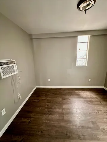 a view of an empty room with wooden floor and window