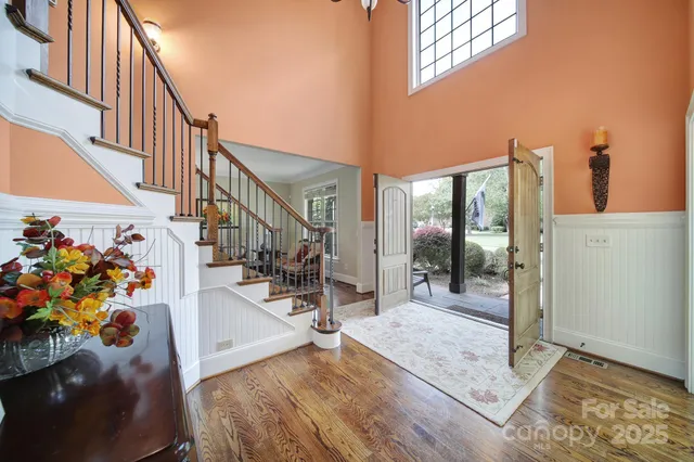 a view of a hallway with wooden floor and a bathroom