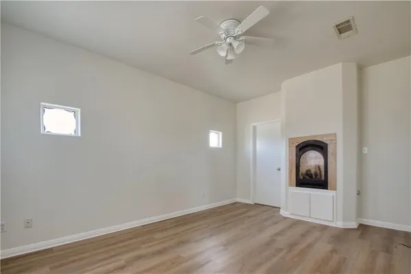 an empty room with wooden floor ceiling fan and window