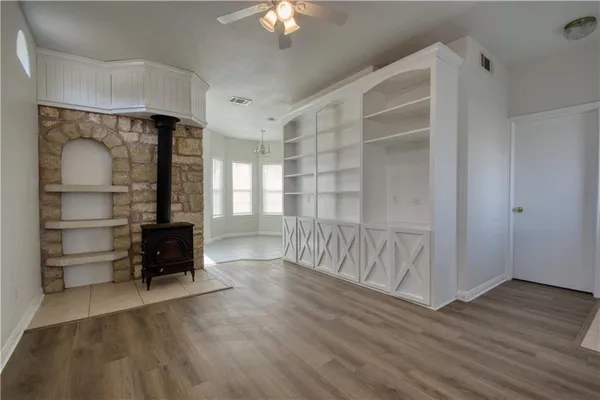 a view of an empty room with a window and wooden floor