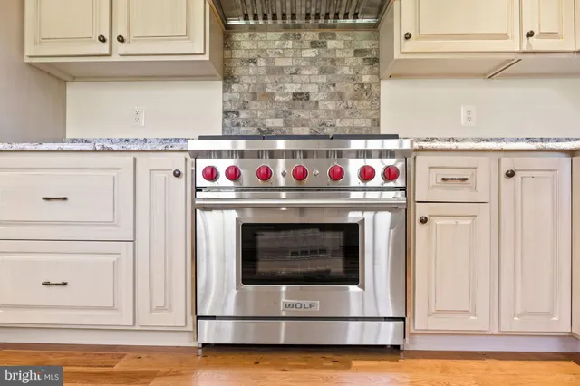 a view of an empty room with wooden floor fireplace and a window