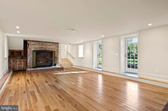 a view of a hallway with wooden floor and a bathroom