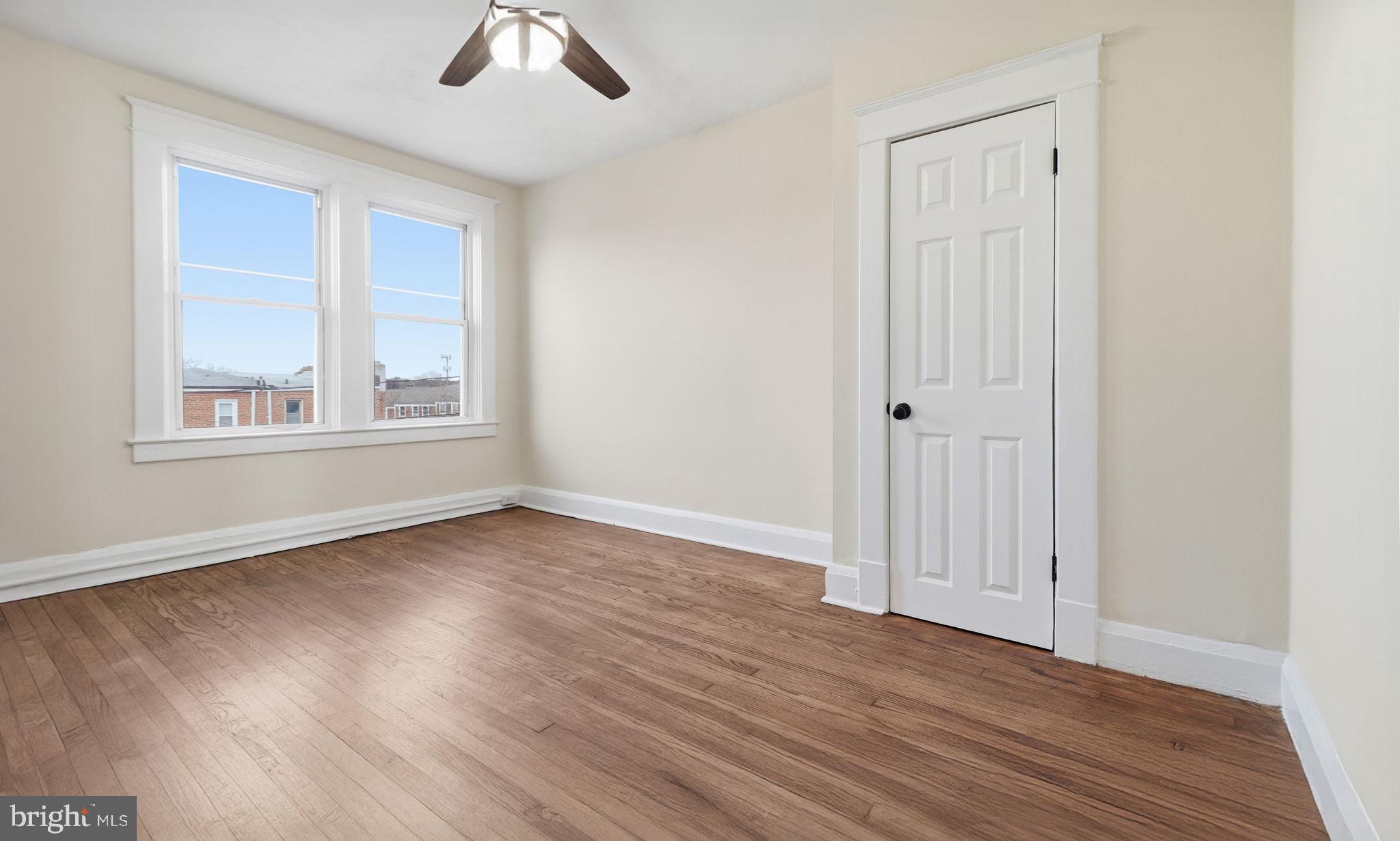 3324 Cliftmont Avenue Baltimore, MD 21213 - Photo 21 of 37 an empty room with wooden floor chandelier fan and windows