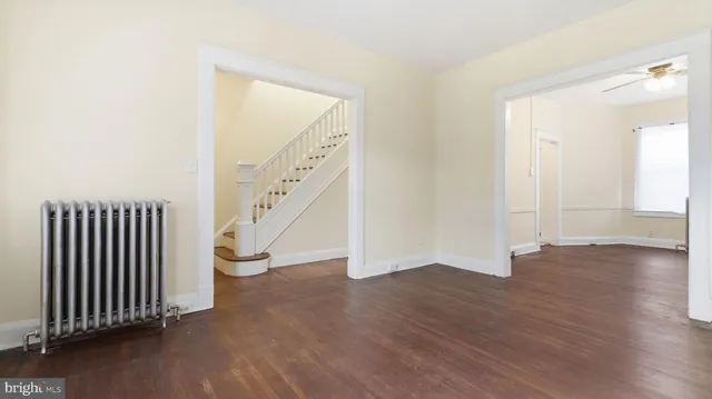 a view of an empty room with wooden floor and stairs