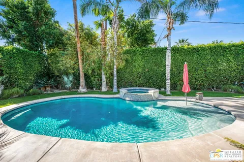 a view of a swimming pool with a yard and palm trees