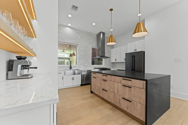 a kitchen with stainless steel appliances a stove a sink dishwasher and a refrigerator with wooden floor