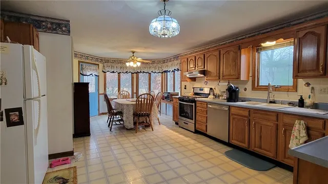 a kitchen with granite countertop a refrigerator stove top oven dining table and a refrigerator