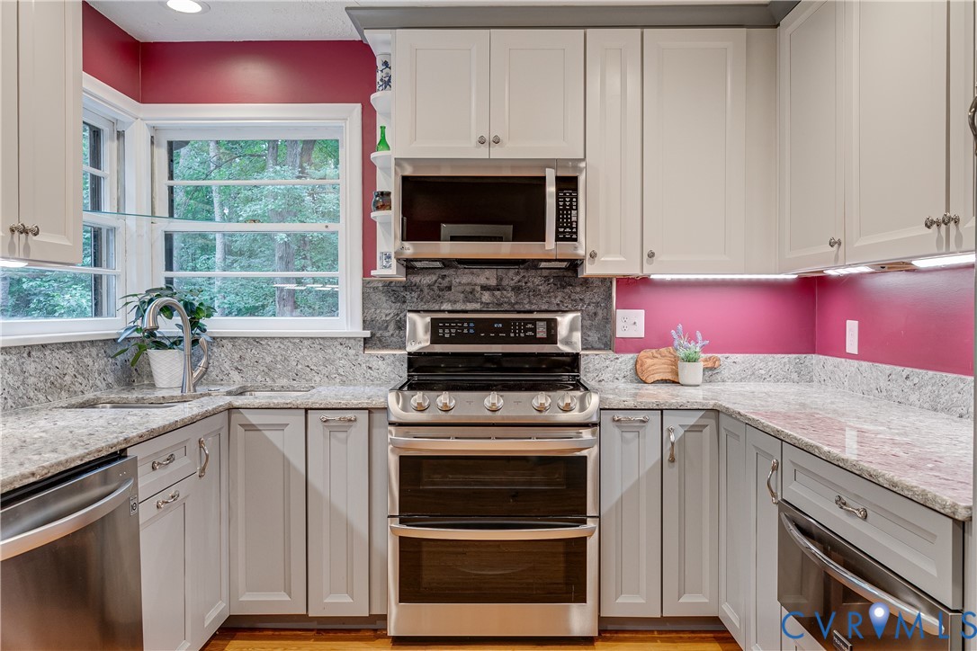 4411 Arrowhead Road Richmond, VA 23235 - Photo 17 of 33 a kitchen with granite countertop a stove top oven cabinetry a sink and a window