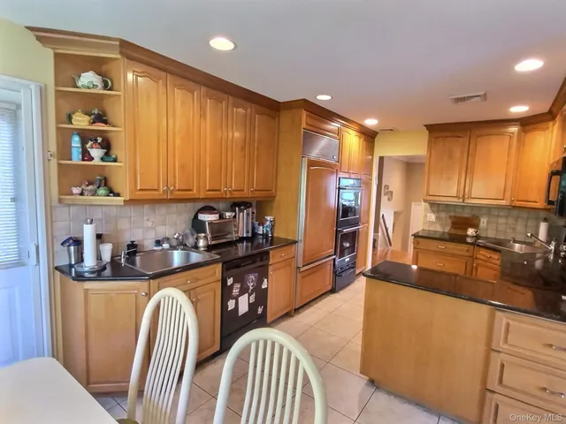 a kitchen with stainless steel appliances granite countertop a refrigerator a sink dishwasher a stove and white countertops with wooden floor