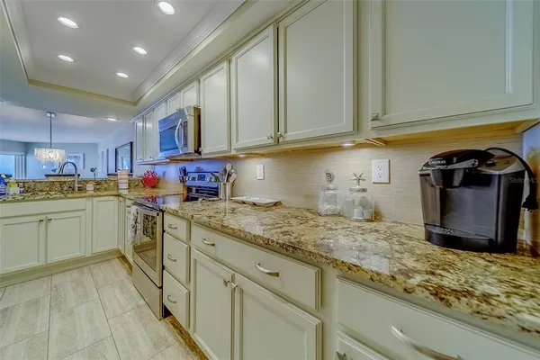 a kitchen with granite countertop a stove top oven microwave and cabinets