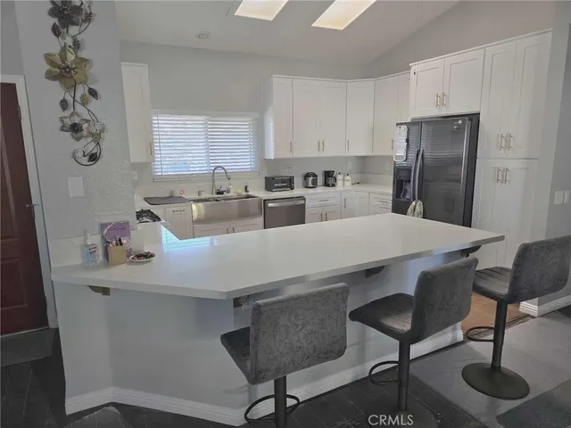 a kitchen with stainless steel appliances a refrigerator a sink a stove and white cabinets