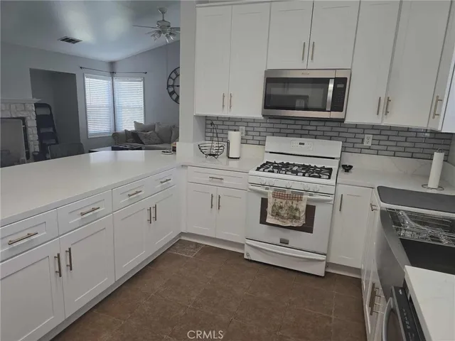 a kitchen with stainless steel appliances granite countertop a stove a sink a refrigerator and white cabinets