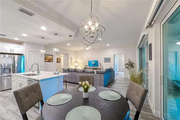 a view of a dining room with furniture a kitchen and chandelier