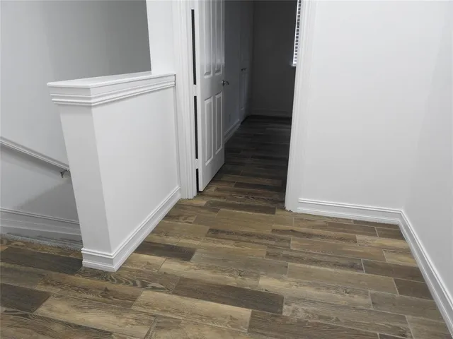 a view of a hallway with wooden floor and staircase