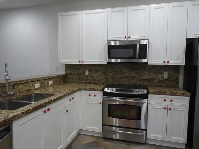 a kitchen with granite countertop white cabinets and stainless steel appliances