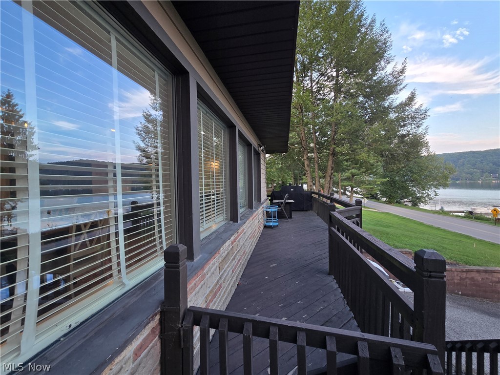 86450 Beaver Dam Road Scio, OH 43988 - Photo 25 of 28 Expansive exterior decking with dark wood-finish railing, brick siding detail, multiple windows, and natural tree scenery