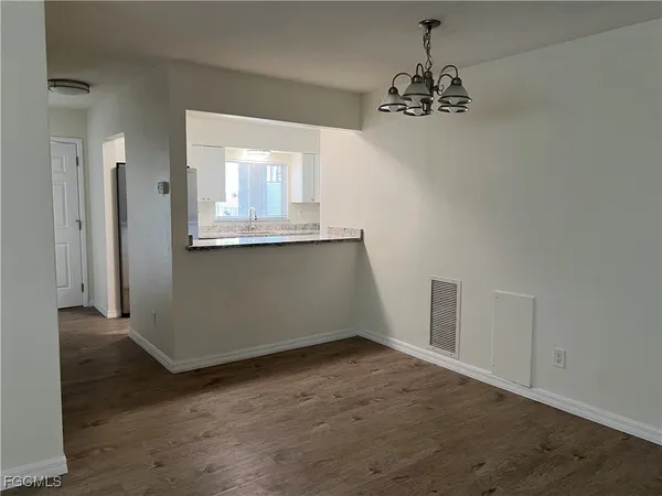 an empty room with a chandelier fan and wooden floor