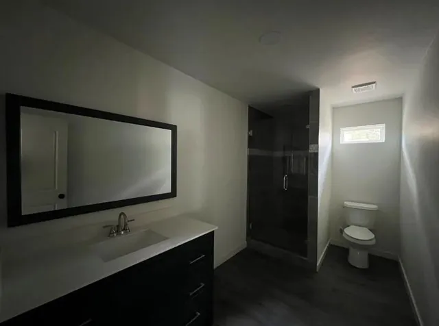 a bathroom with a granite countertop sink toilet and mirror
