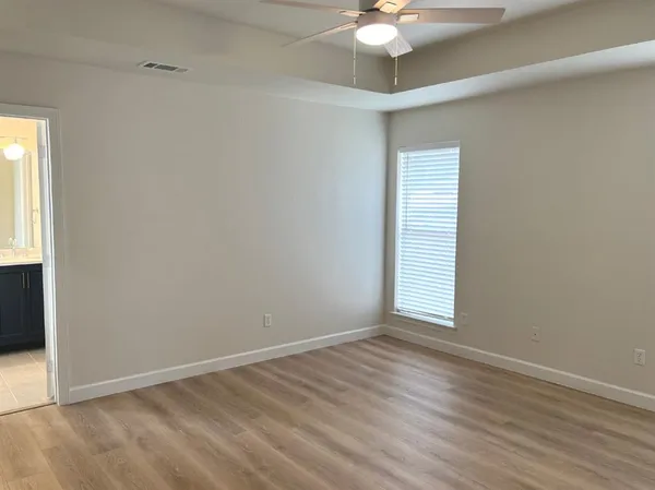 an empty room with wooden floor fan and windows