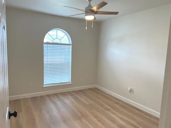 an empty room with a window and ceiling fan