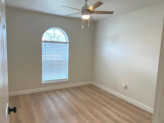 an empty room with a window and ceiling fan