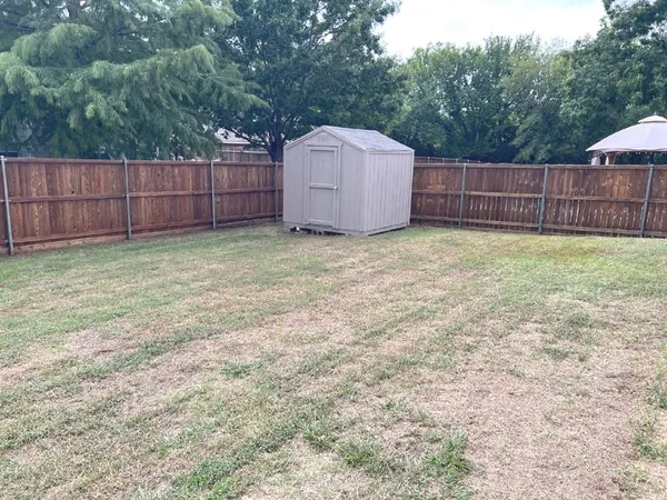 a backyard of a house with a small barn and wooden fence
