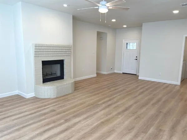 an empty room with wooden floor fireplace and windows