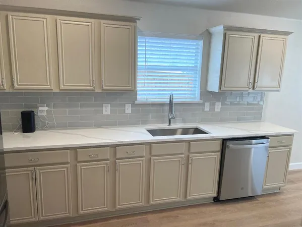 a kitchen with white cabinets and sink