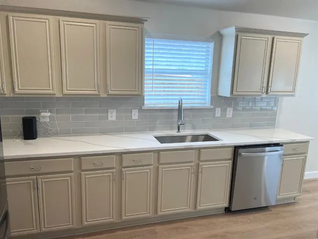 a kitchen with white cabinets and sink