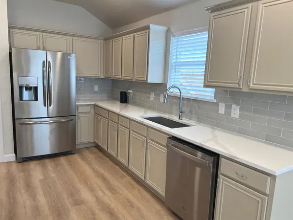 a kitchen with a sink a refrigerator and cabinets