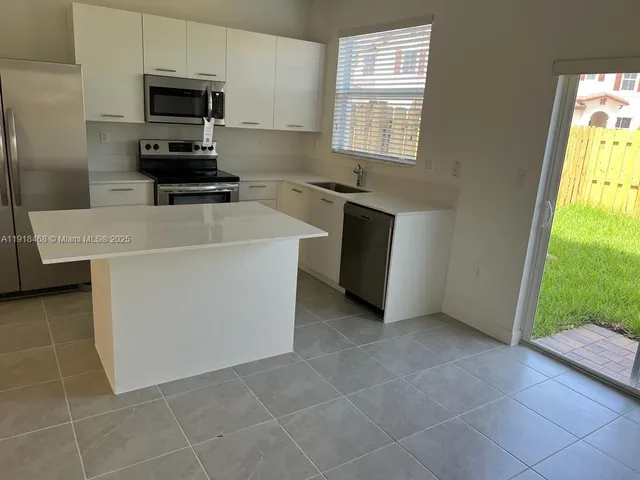 a kitchen with granite countertop white cabinets and stainless steel appliances