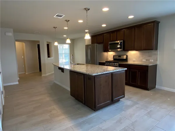 a kitchen with stainless steel appliances granite countertop a stove a sink and a refrigerator