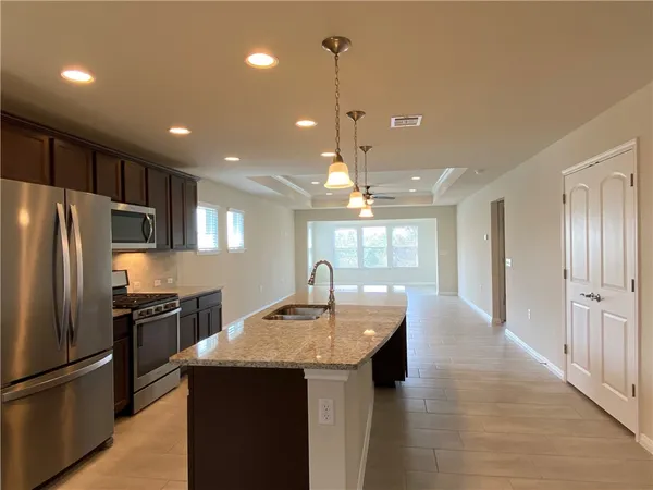 a kitchen with kitchen island granite countertop a refrigerator a sink dishwasher and a stove top oven