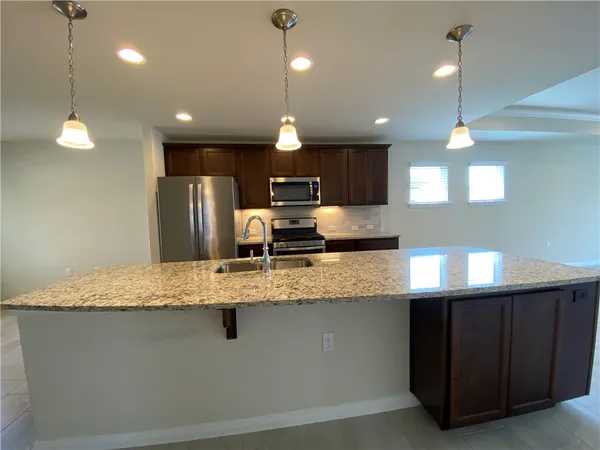 a kitchen with kitchen island granite countertop a refrigerator a sink and a stove