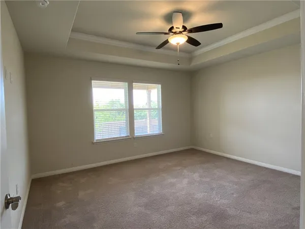 an empty room with a chandelier fan and windows