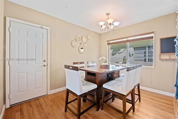 a dining room with wooden floor a chandelier a wooden table and chairs