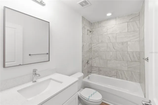 a bathroom with a bathtub shower sink vanity mirror and toilet