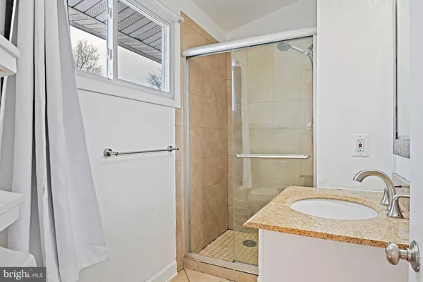 a bathroom with a granite countertop sink toilet and shower
