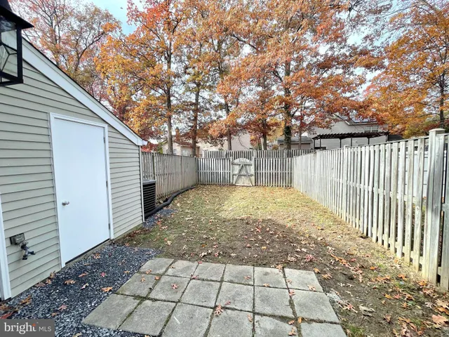 a view of backyard with large trees and wooden fence