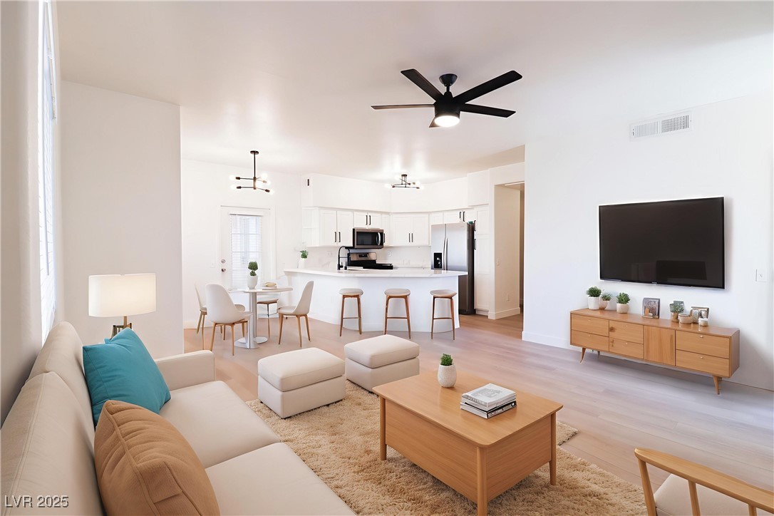 Living room with light wood finished floors and ceiling fan